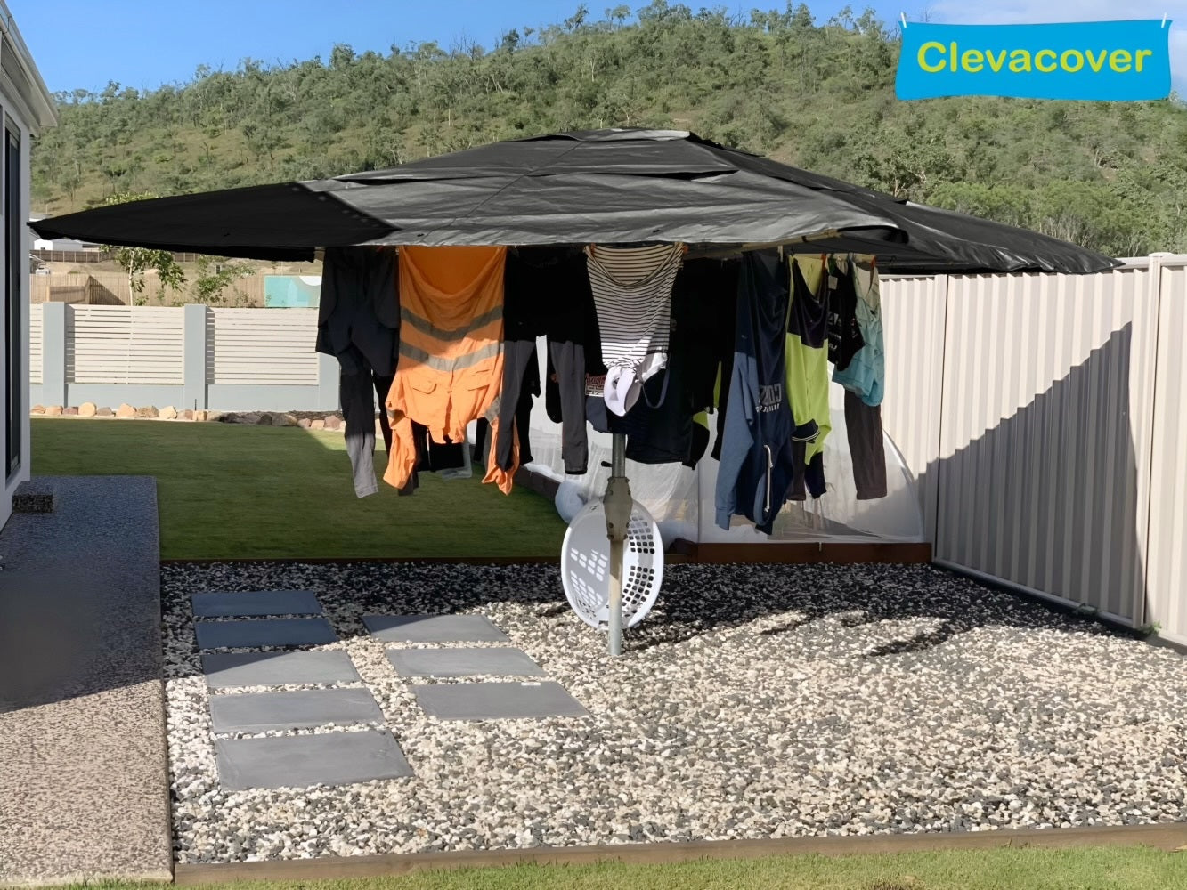 Clothes hanging on a clothesline under a Clevacover canopy with a scenic background.