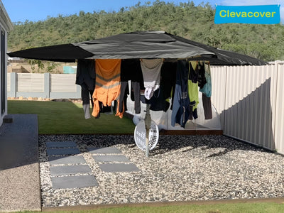 Clothes hanging on a clothesline under a Clevacover canopy with a scenic background.